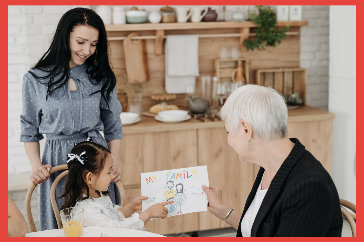 Family. Girl with art of her family. CASA volunteer. All sitting around table. 